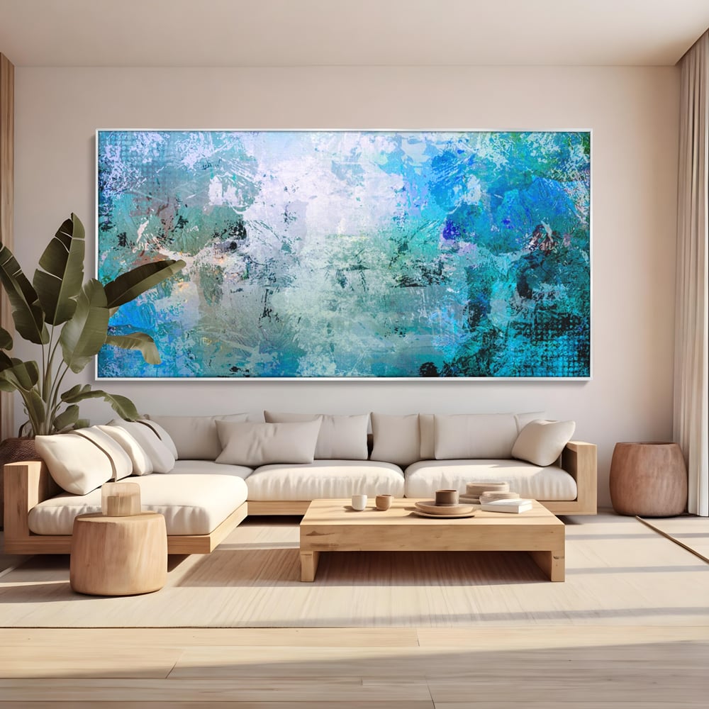 Tablou canvas cu pictura abstracta cu pete de albastru, in rama de aluminiu argintiu, pe perete intr-un living